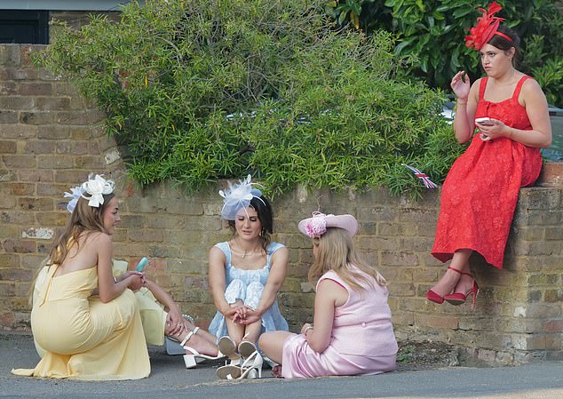 A group of ladies take a seat on the pavement to get out of the sun