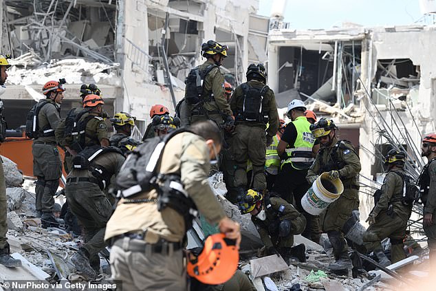 Rescue teams inspect a damaged building following a strike by an Iranian ballistic missile in Bat Yam on June 15