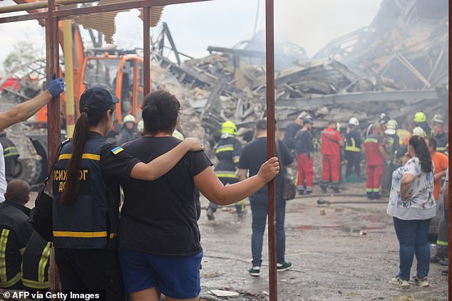 People watch as Ukrainian rescuers dismantle the rubble of a destroyed administrative building in the center of Odesa after a missile strike on July 20, 2023