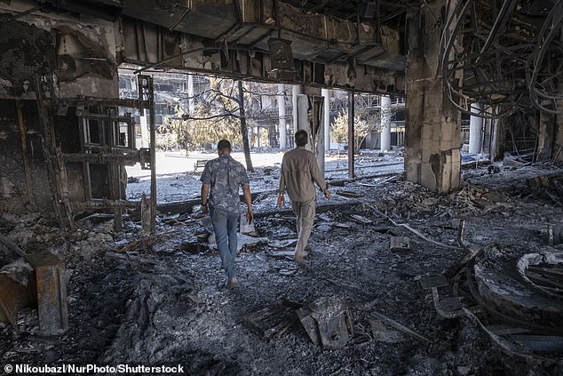 Two men walk through the debris of the headquarters of the Islamic Republic of Iran News Network after an Israeli strike on Iran's state television compound