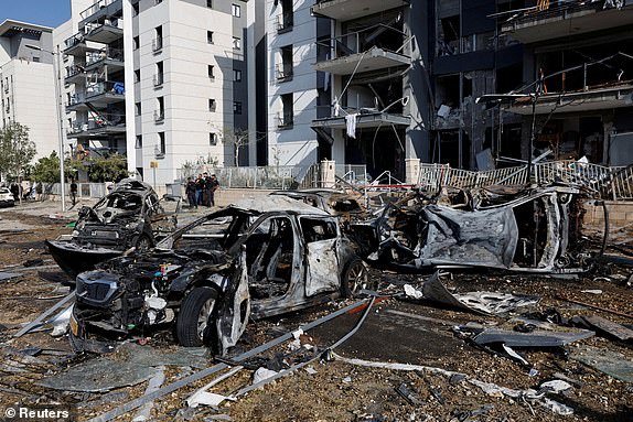 Emergency personnel work next to burnt cars and damaged residential buildings at an impact site following Iran's missile strike on Israel, in Be'er Sheva, Israel, June 20, 2025. REUTERS/Amir Cohen