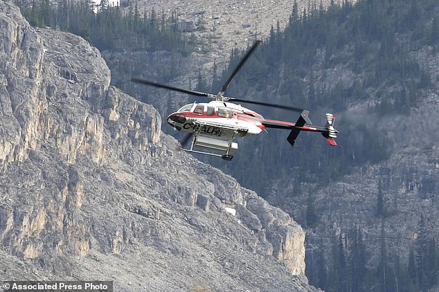 Pictured: A helicopter is seen close to the scene of the rockslide on Thursday looking for survivors. Search efforts will continue into Friday