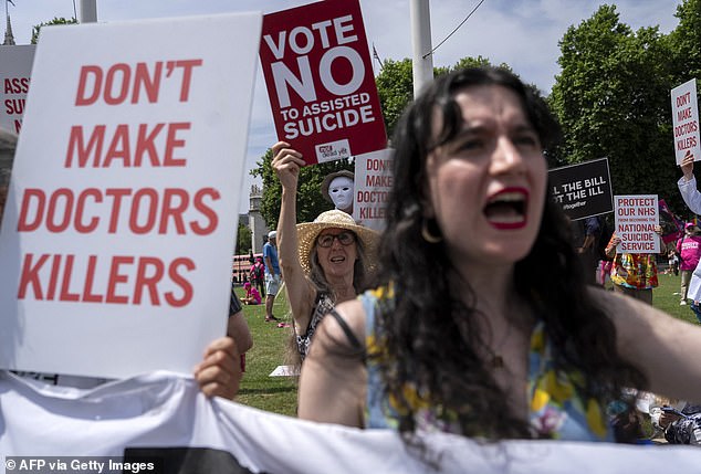 Protesters against a change in the law on assisted dying hold placards during a demonstration outside Parliament