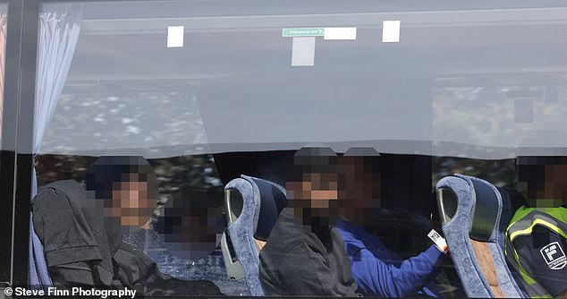 Migrants are seen arriving by coach and heading into Manston Processing Centre on June 18