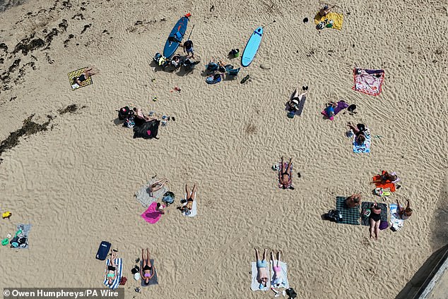 The sizzling sunshine means levels of ultraviolet radiation are likely to reach high or very high levels, with the humid conditions sparking thunderstorms. Pictured: People enjoy the hot weather at Cullercoats Beach in North Shields