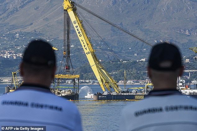 Guard Coast crew looks at crane ships 'Hebo Lift' that is slowly raising the superyacht Bayesian