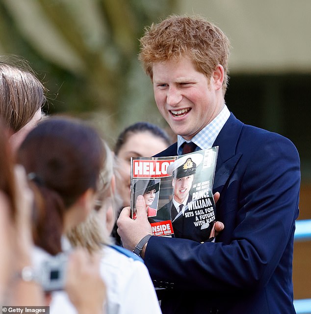 Prince Harry holds up a copy of Hello Magazine featuring photographs of Kate Middleton and his brother Prince William on the cover in June 2008