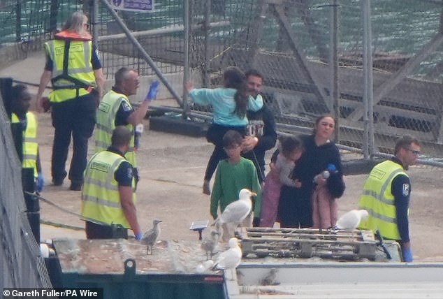 A young girl waves to security officers as a group of people thought to be migrants are brought in to Dover, Kent, from a Border Force vessel following a small boat incident in the Channel on June 20