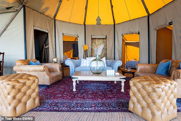 The glamping tent includes a luxurious living room with quilted furniture and armchairs