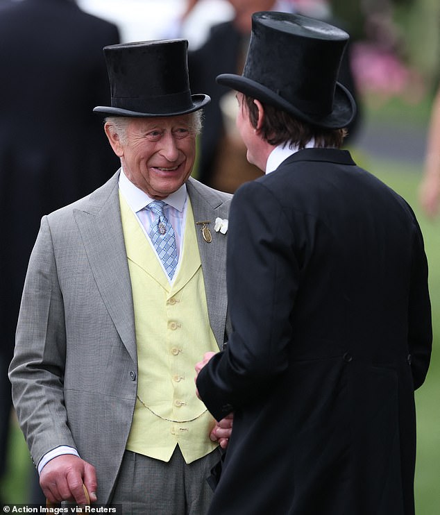 SMILE: The King appeared to be enjoying himself as he was photographed chatting with a fellow guest at the Berkshire racecourse