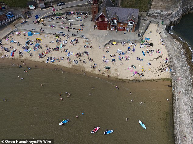 An official heatwave is recorded when areas reach a certain temperature for three consecutive days, with thresholds varying from 25C to 28C in different parts of the UK (Pictured: Beachgoers at Cullercoats Bay, North Tyneside, June 21, 2025)