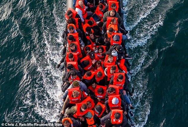 Pictured: An inflatable dinghy carrying migrants makes its way towards England