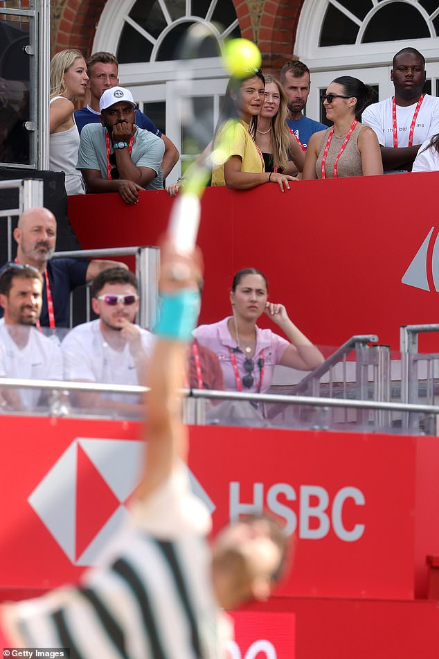 Emma Raducanu is seen in the background on the balcony as Alcaraz serves during his semi-final
