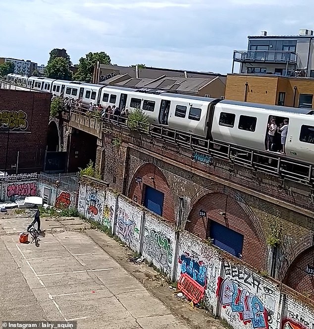 The train, which had stopped moving, left many onboard feeling as though they were being 'slow cooked' in 'an oven' amid the sizzling 34C heat. In the footage shared to X, the stranded passengers scream in delight each time the man successfully throws a bottle within catching distance as they helplessly stand still at the open train doors during the heatwave