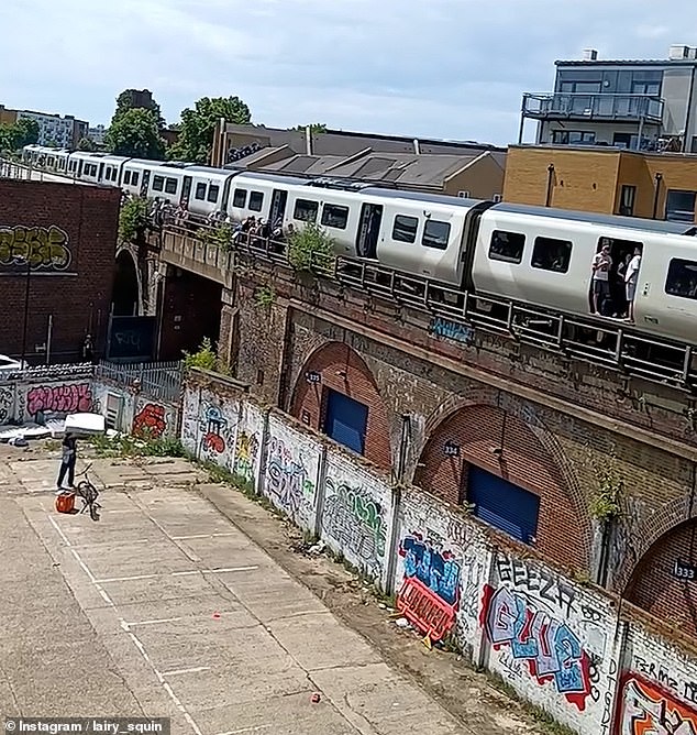 Coming to the rescue of the parched travellers, the Just Eat driver is shown standing on the ground with an orange bag full of bottled water, which he carefully aims up at the train which is stuck still on a bridge above him