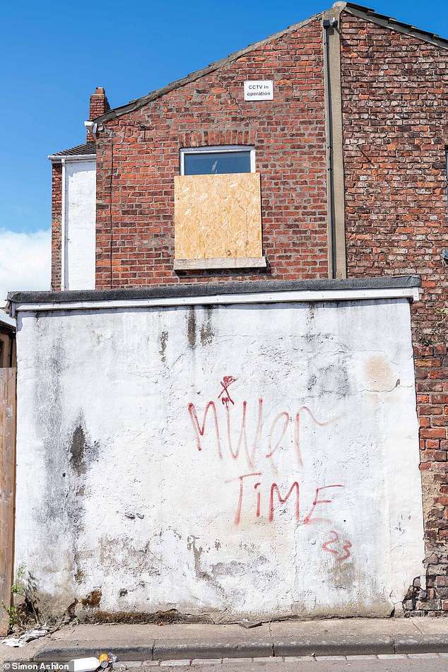 Graffiti on a wall of one of the properties on the road reads 'Miller Time'
