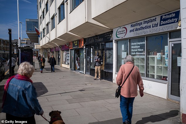 Locals walk down a street in Hastings in March last year