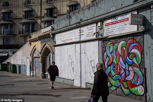 People pass boarded up shops in Hastings, March 2024