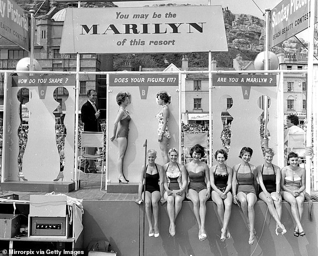 This photo shows female holidaymakers competing in a Marilyn Monroe lookalike contest in Hastings in 1958. The women were required to fit inside a cutout of the famous actress' body