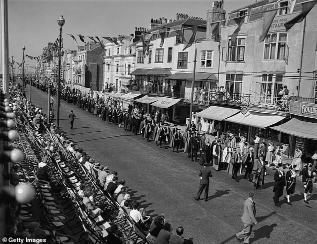 In this photo, a crowd is seen gathering to see Winston Churchill who travelled to Hastings in 1955. On his visit, Churchill joined the Winkle Club, a group founded by local fishermen. All of the club members were required to carry a winkle and Churchill's was made of solid gold