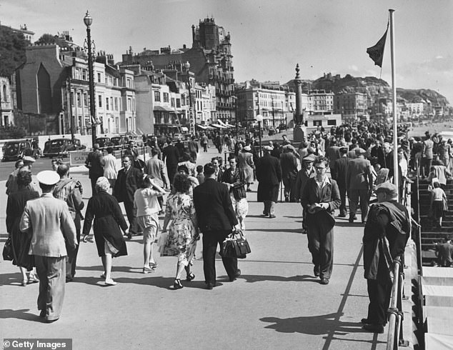 This picture shows Hastings' promenade and seafront packed with holidaymakers in 1951. The castle ruins can be seen on top of the hill at the back of the image