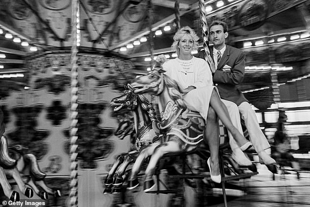 A young holidaymaker rides the merry-go-round with a Butlins Redcoat at the Butlins Holiday Camp in Bognor Regis, 1985