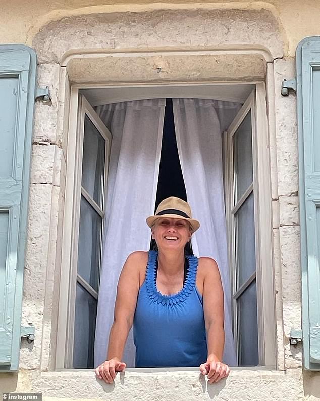 The presenter beams from a balcony of a villa in Morestel in France in July 2023