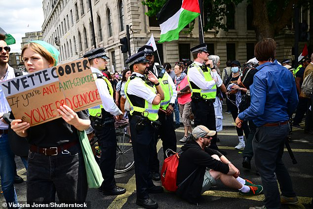 An activist sits on the floor in front of police officers during the protest on monday