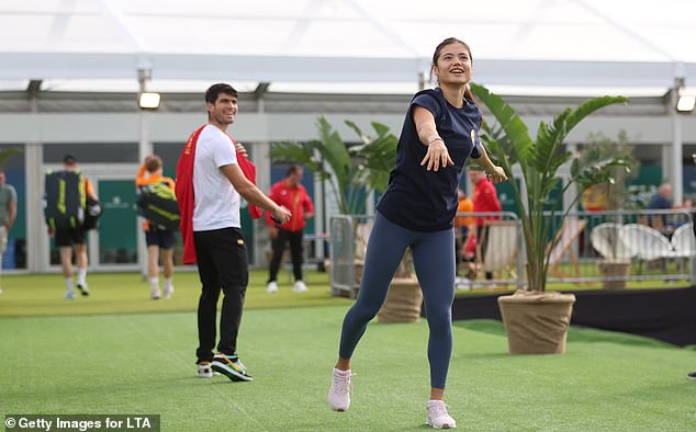 Raducanu throws a ball while Alcaraz watches on in November last year at the Billie Jean King Cup