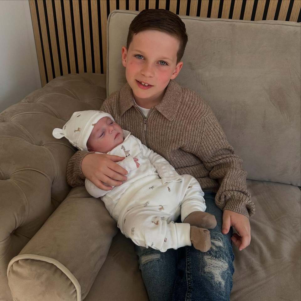 Older brother holding his baby brother on a couch.