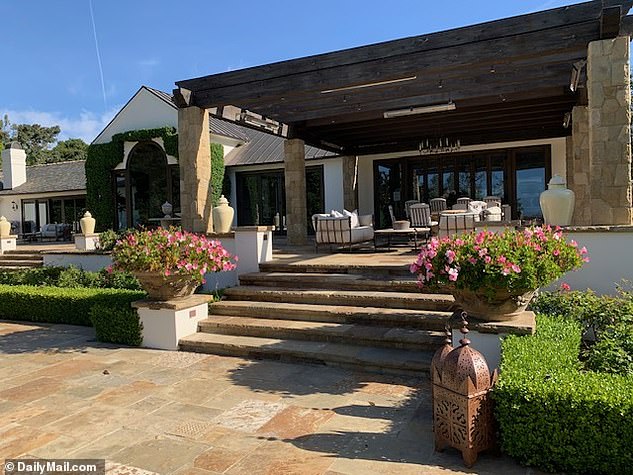 The Montecito mansion's back entrance is complemented with blooming pink flowers and sculpted hedges surrounding the patio