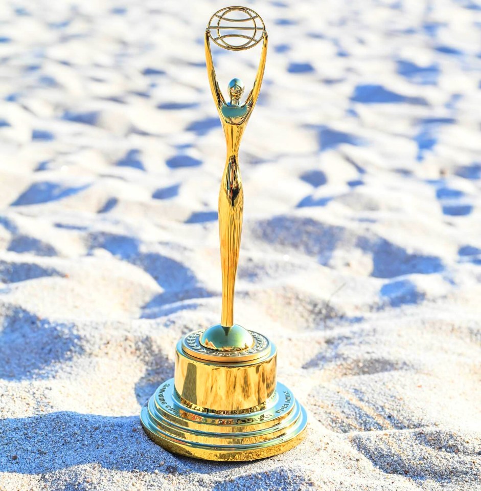 A gold Clio Sports Award on a beach.