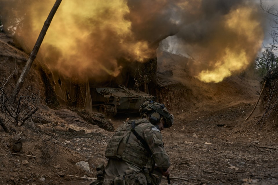 Soldier near military vehicle amidst smoke and fire.