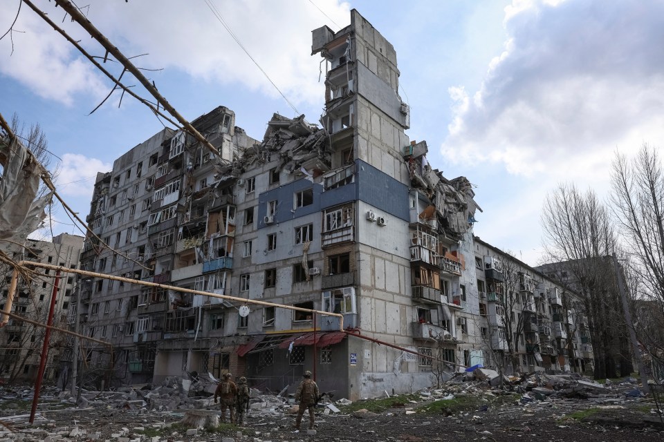 Damaged apartment building in Pokrovsk, Ukraine, with police officers present.