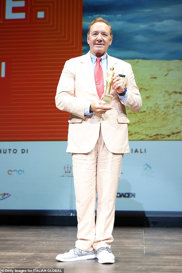 Kevin wore a light pink suit with a red tie and light blue shirt for the summer weather as he walked the red carpet as he picked up an award