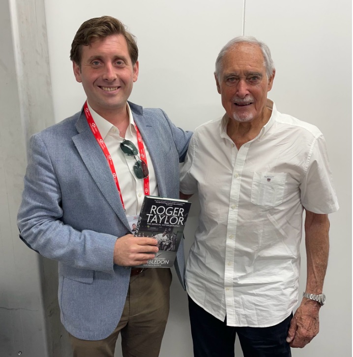 Roger Taylor with a man holding his autobiography.