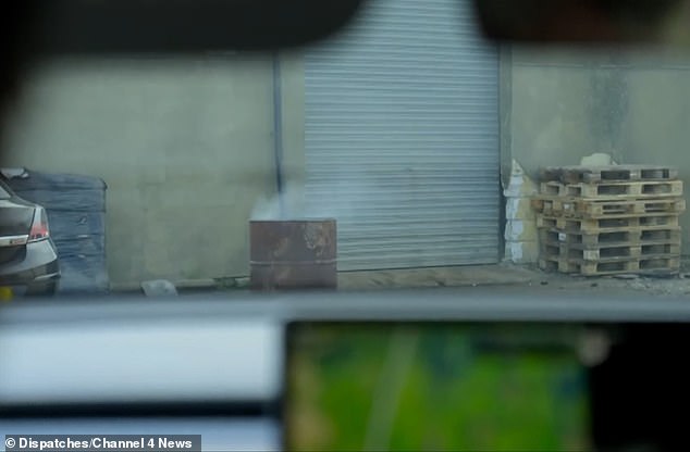 Glancing inside, you can see piles of wooden pallets, garages, parked vans and shipping containers