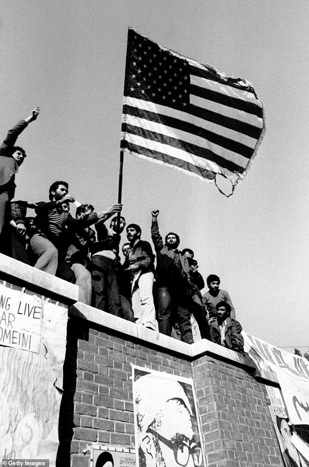 In the days that followed the revolution, students who backed Khomeini stormed the US Embassy in Tehran and took 66 of its staff hostage for 444 days. Above: Students burning a US flag as they stand on the walls of the U.S. embassy compound