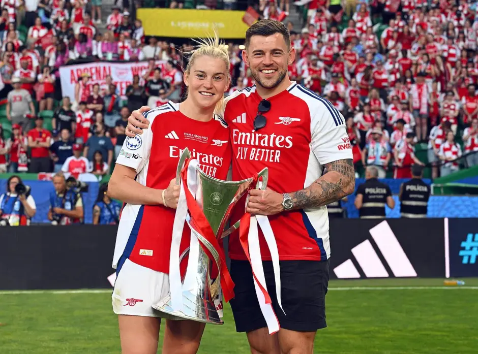 Arsenal women's team celebrating a victory with a trophy.