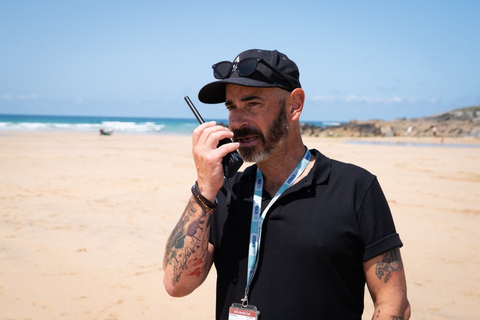 Man on beach using walkie-talkie.
