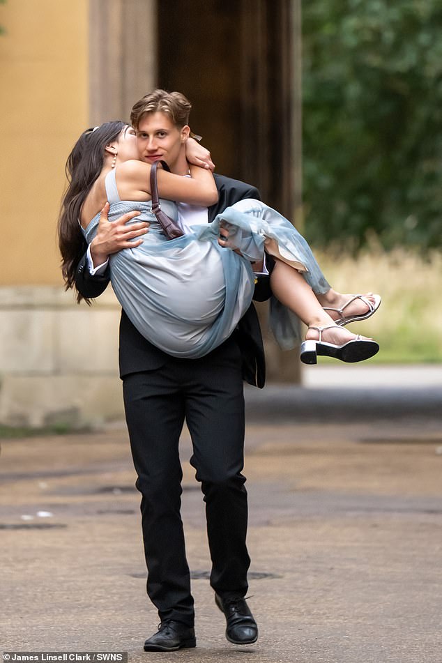 A man is pictured carrying a woman the morning after spending the evening partying away at Trinity Ball
