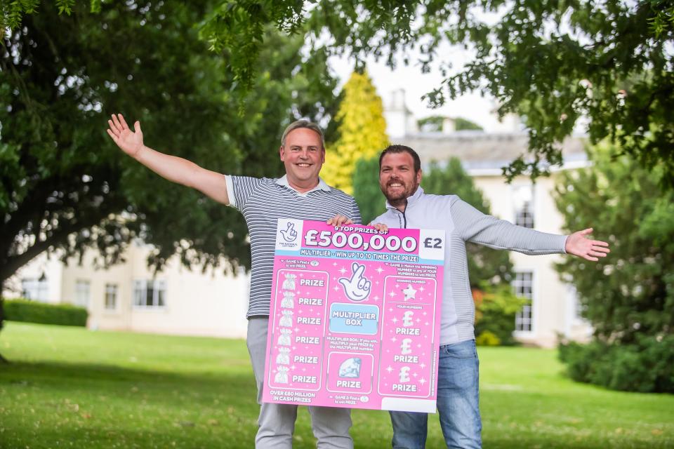 Two men holding a £500,000 winning lottery scratchcard.