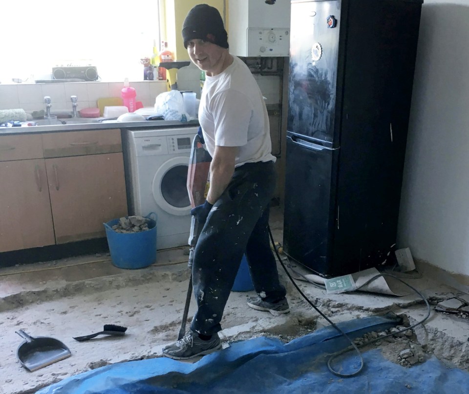 Man using a jackhammer to break up a kitchen floor.