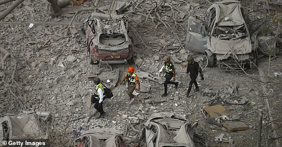 BEERSHEBA, ISRAEL - JUNE 24: Emergency responders walk amid damaged cars at a building where at least four people died in a missile strike on June 24, 2025 in Beersheba, Israel. According to Israeli authorities, Iran launched a barrage of missiles in the early hours this morning, before the start of a purported U.S.-brokered ceasefire between between the two countries. The Iranian foreign minister said that, if Israel stopped its attacks as of this morning, Iran would also end its strikes. (Photo by Amir Levy/Getty Images)