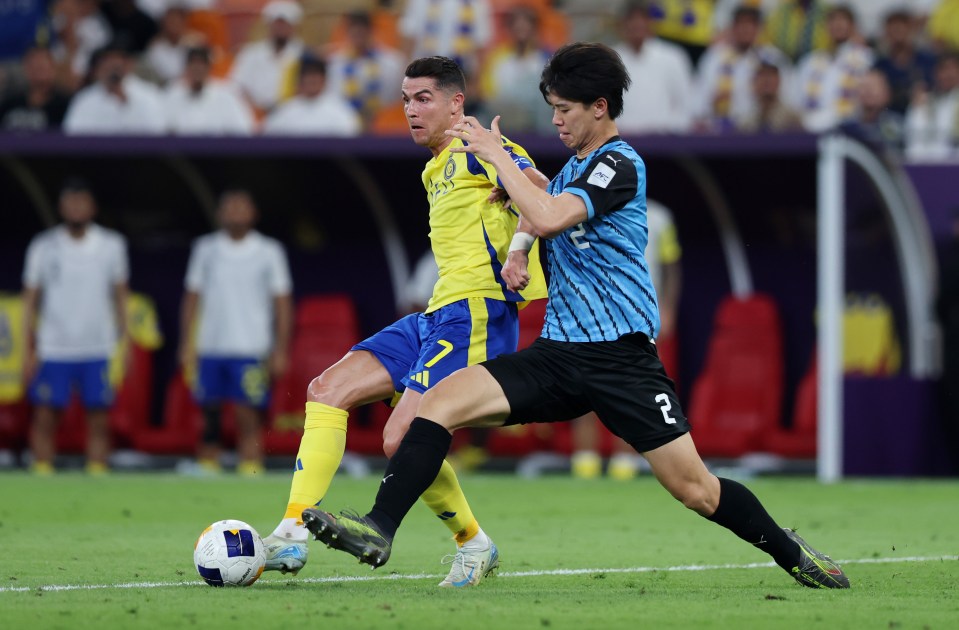 Cristiano Ronaldo of Al Nassr challenged by Kota Takai of Kawasaki Frontale during a soccer match.