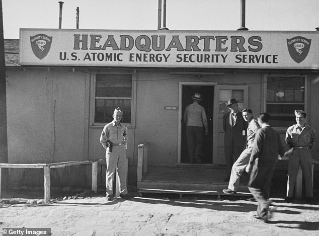 A group of men outside the entrance, which is guarded by Military Police, to the headquarters of the United States Atomic Energy Security Service at Los Alamos, New Mexico, September 1947