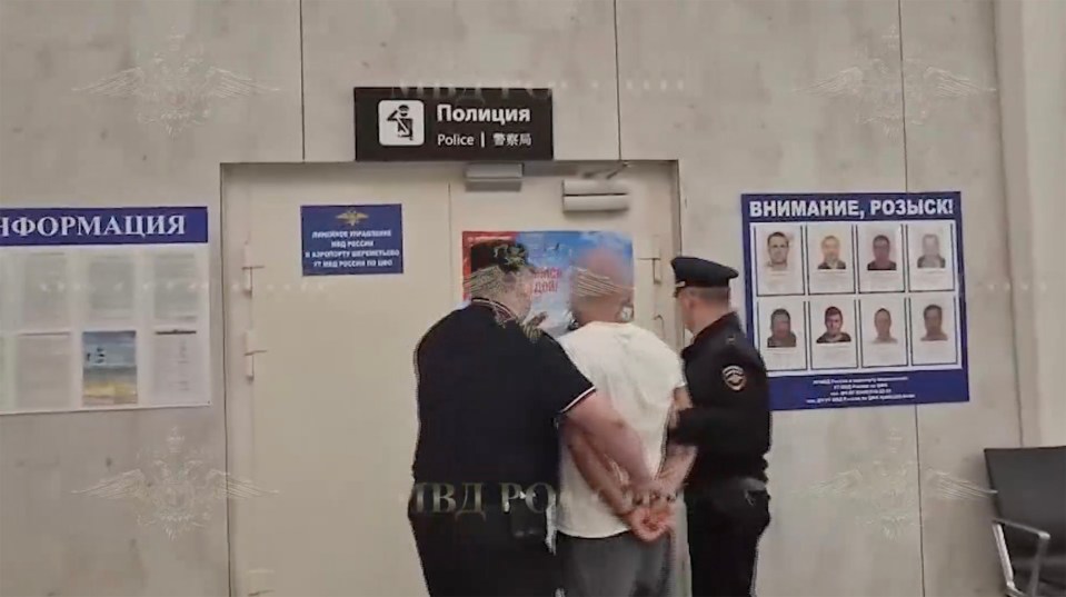 A man in handcuffs being escorted by police officers.