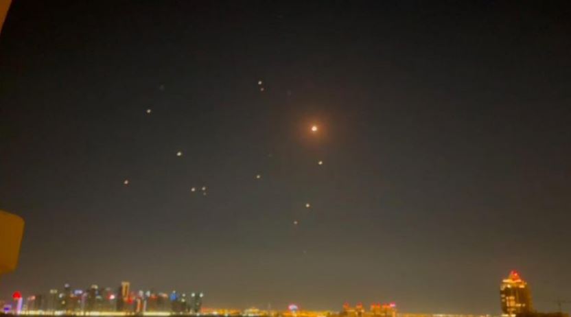 Night sky over a city at night with a bright object and several smaller lights visible.