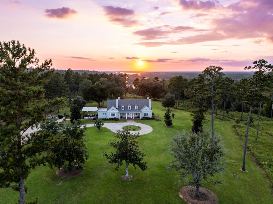 Aerial view of a large house on a sprawling ranch at sunset.