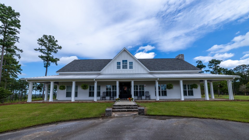White farmhouse with wraparound porch.